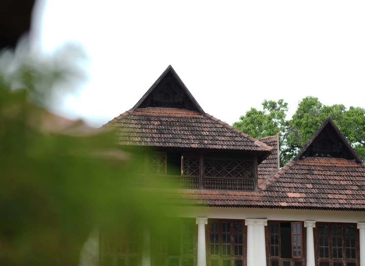 Traditional tiled-roof building seen through greenery