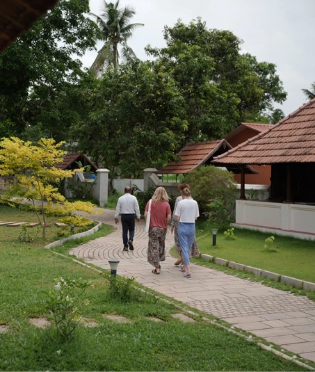 Guests walking along a paved path between lawns and tiled-roof villas